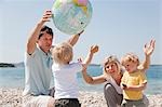 Familie mit Zwillingen am Strand spielen ball