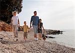 Famille avec chien marchant sur la plage