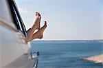 Woman stretching feet from car by sea