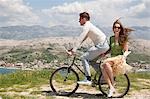 Couple riding bike by sea