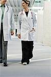 Female doctor walking with colleague along hospital corridor