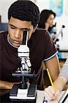 High school student looking through microscope