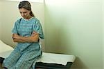 Female patient sitting on examination table waiting for doctor