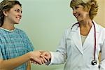 Doctor shaking hands with patient, both smiling