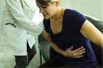 Doctor assisting patient with severe abdominal pain