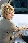 Woman checking road map, smiling at camera