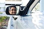 Homme assis dans une voiture garée, reflet dans le miroir de vision latérale