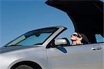 Woman putting convertible top down preparing for drive on summer day