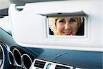 Woman in car using visor vanity mirror to put on make-up