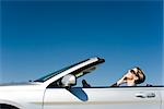 Woman talking on cell phone while driving convertible