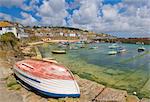 Small unturned boat on the quay and small boats in the enclosed harbour at Mousehole, Cornwall, England, United Kingdom, Europe