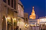 The restored Souq Waqif looking towards the illuminated spiral mosque of the Kassem Darwish Fakhroo Islamic Centre based on the Great Mosque of Samarra in Iraq, Doha, Qatar, Middle East