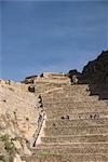 Tourists on huge stone terraces in the Inca ruins of Ollantaytambo, The Sacred Valley, Peru, South America