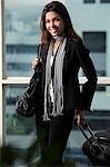 young woman holding bag and pulling suitcase