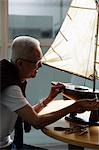 profile of older man working on model sail boat