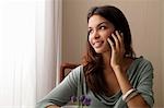 young woman talking on phone looking out window