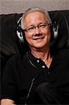 mature man with grey hair wearing head phones and smiling