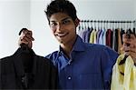 young man holding up two shirts and smiling