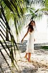 young woman walking on beach with coconut trees in background