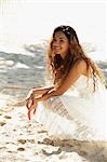 young woman sitting on sand at the beach smiling