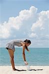 young woman picking up rubbish on the beach