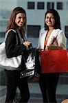 deux femmes tenant des sacs à provisions et souriant