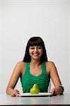 woman holding plate with green pear and smiling