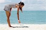 young woman picking up rubbish on the beach