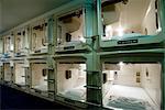 Rows and stacks of sleeping compartments along one corridor at a capsule hotel in Osaka, Japan, Asia