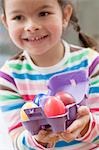 Girl with coloured Easter eggs in an egg box