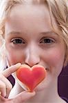 Young woman holding a heart in front of her mouth