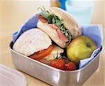 Two sandwiches, apple and tomatoes in a lunch box