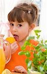 Girl licking a lemon beside jug of lemonade