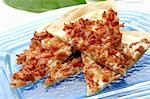 Pieces of tarte flambée with onion and bacon topping