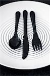 Black plastic cutlery on a plate