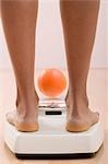 Young woman on bathroom scales with orange