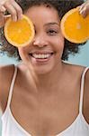 Young woman holding orange slices in front of her face