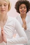 Two young women meditating with eyes closed