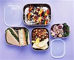 Salads, vegetable kebabs and sandwiches in lunch boxes