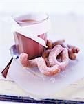 A glass of hot chocolate with curly doughnuts