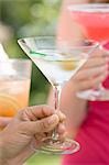 Hand holding glass of Martini, woman with strawberry drink