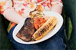 Woman holding plate of grilled steak and accompaniments