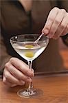 Woman spearing olive in Martini glass