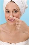 Femme tamponnant crème pour le visage sur son nez