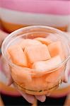 Woman holding plastic tub of diced melon