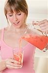 Woman pouring pink grapefruit juice into glass