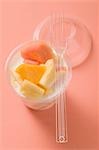 Yoghurt with fresh fruit in plastic pot, fork on pot