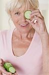Woman holding a slice of cucumber in front of her eye