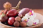 Assorted exotic fruits in a dish with orchids