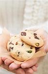 Hands holding chocolate chip and cranberry cookies